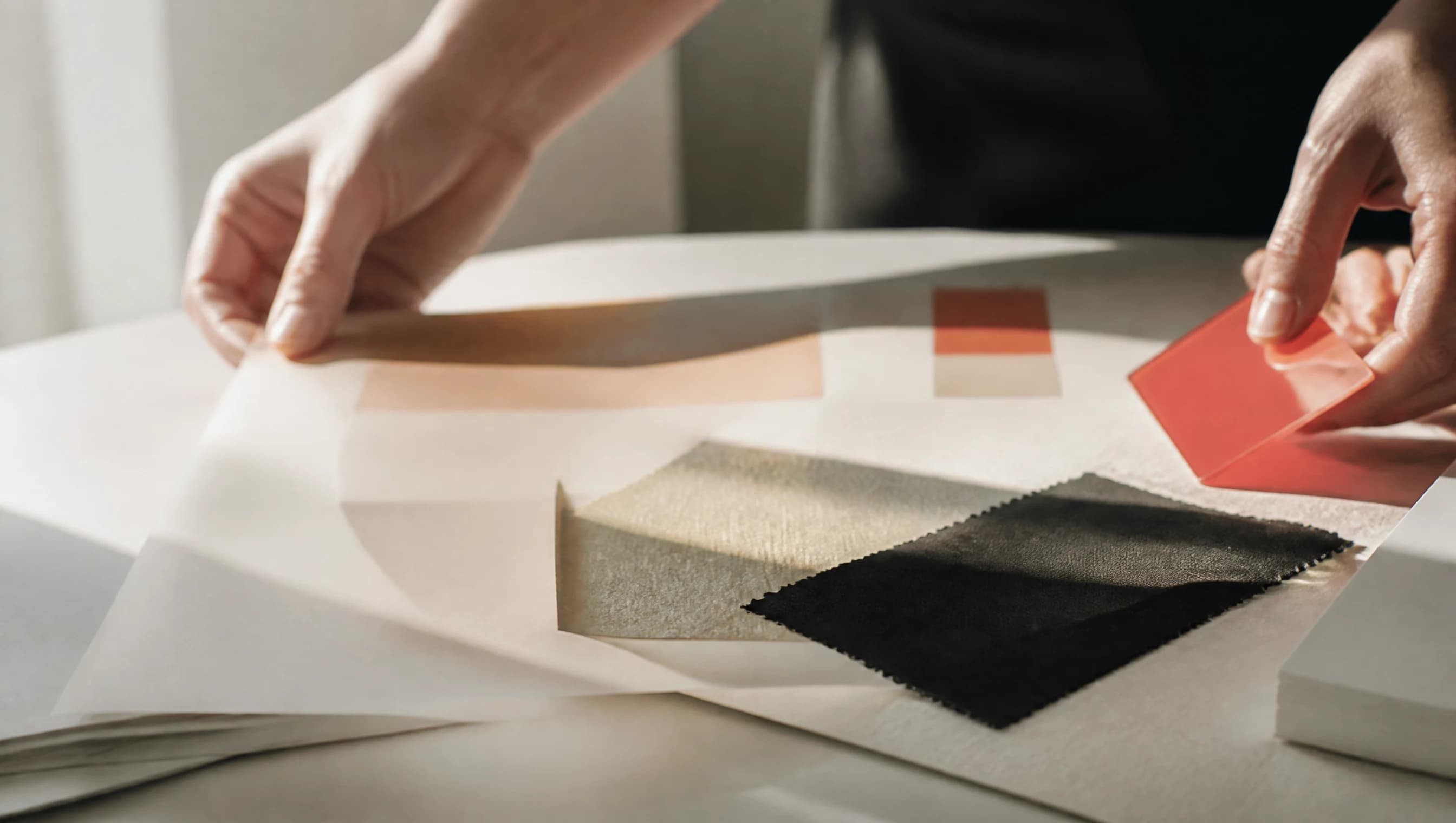 Hands compare paper, fabric and color samples in warm daylight