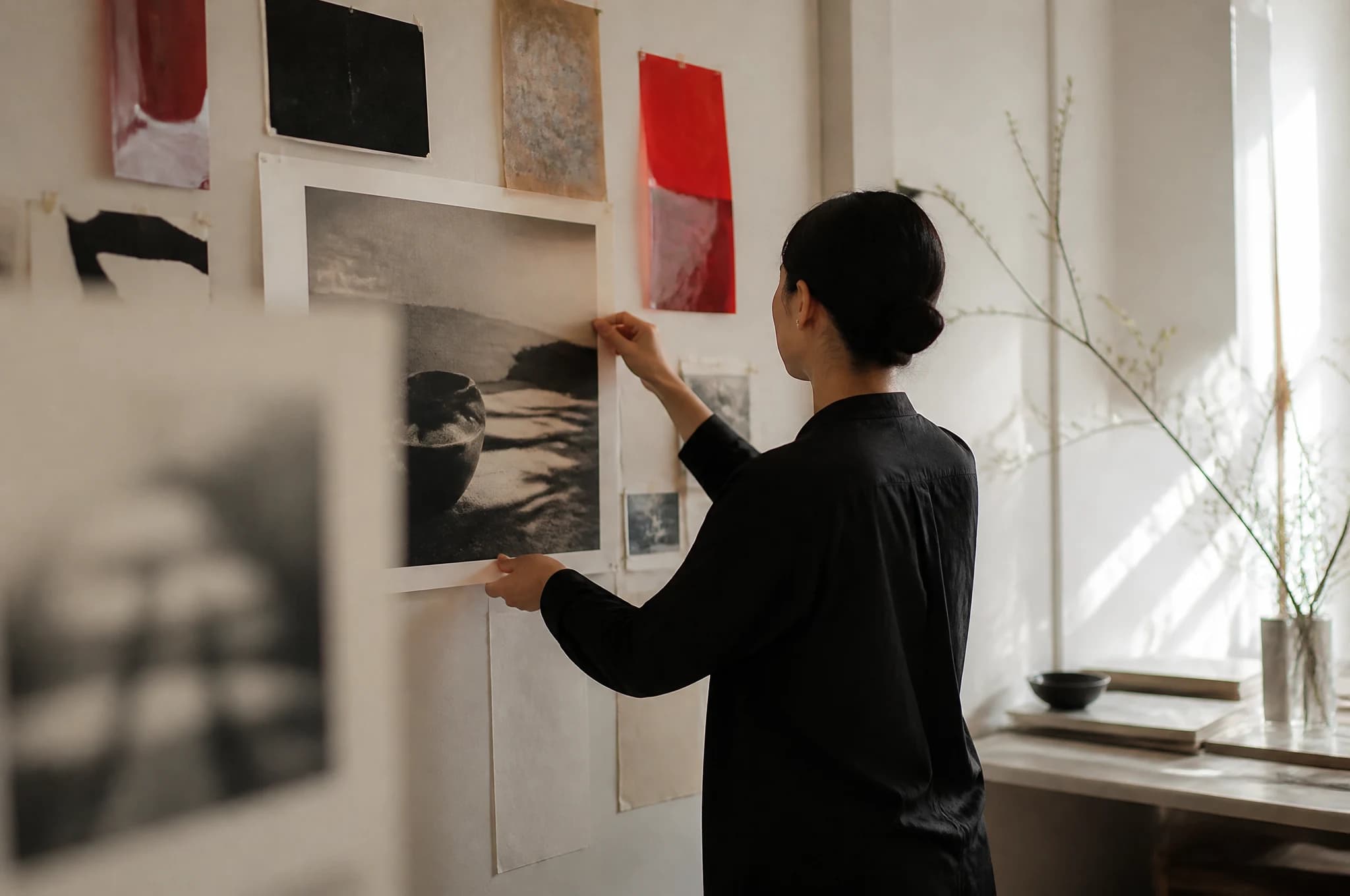 A designer arranges a red, black and ivory identity system on a studio wall